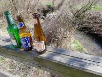Drei kleine Bierflaschen am Brückengeländer